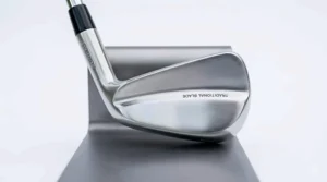 A close-up, high-definition photograph of a traditional forged muscle back golf iron, highlighting its sleek, polished carbon steel blade, minimal offset, and thin topline designed for advanced shot shaping, presented against a minimalist white background with natural daylight.