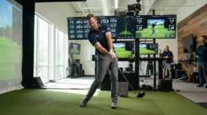 A golfer testing a professional golf driver for high swing speed during an indoor launch monitor fitting session.